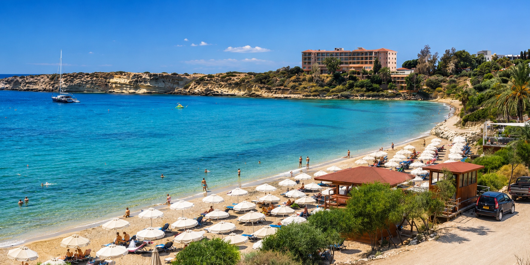 Sunny Coral Bay beach with turquoise water and beach umbrellas on the BiRide e-bike route from Paphos