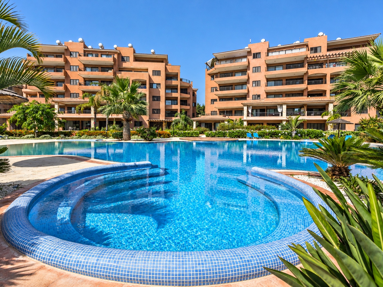 Großer Außenpool vor Apartments im mediterranen Stil in einer Ferienanlage