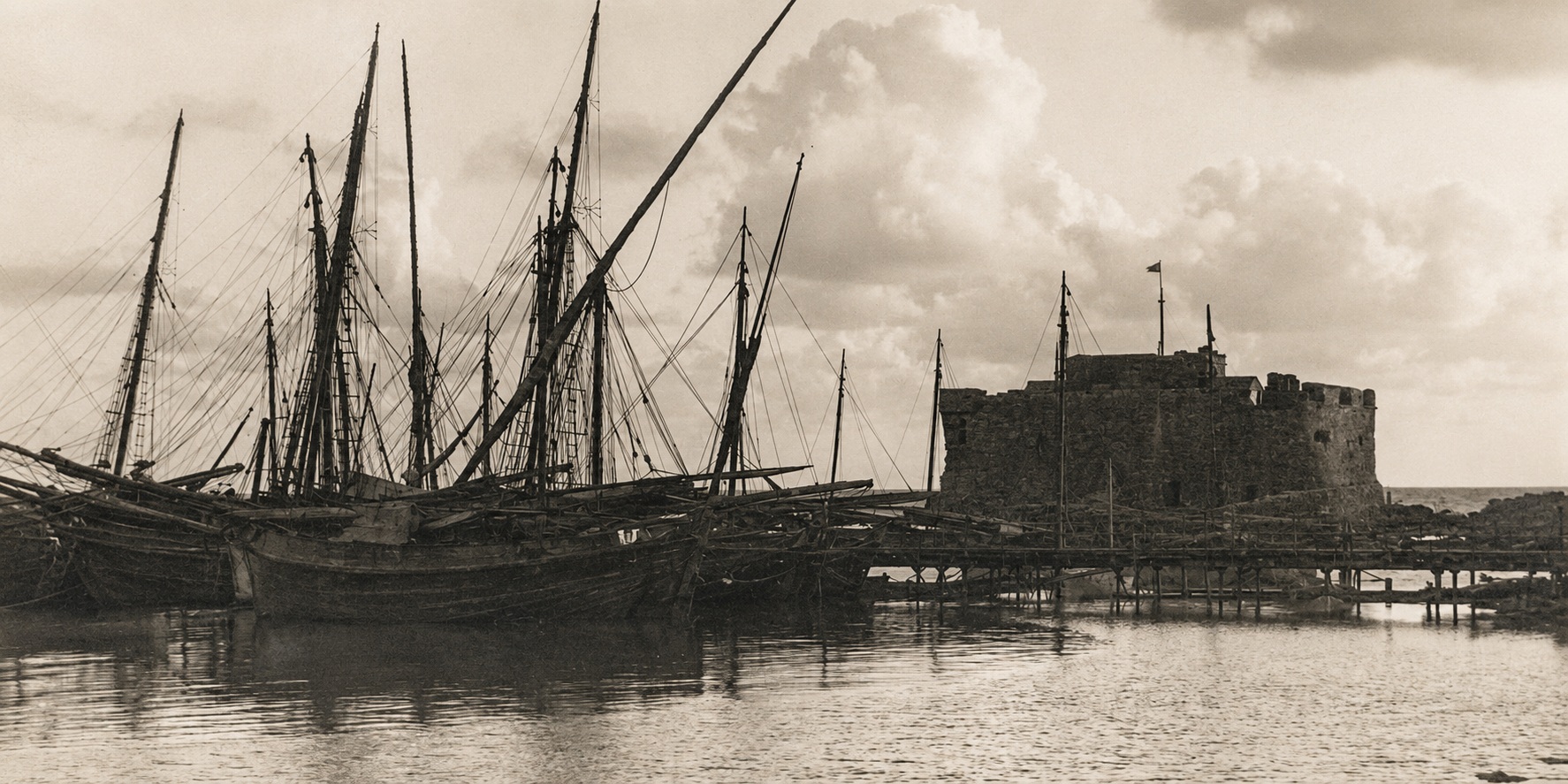 Digitally restored archival view of sailing boats beside Paphos Castle between 1927 and 1931, during its use as a British salt store