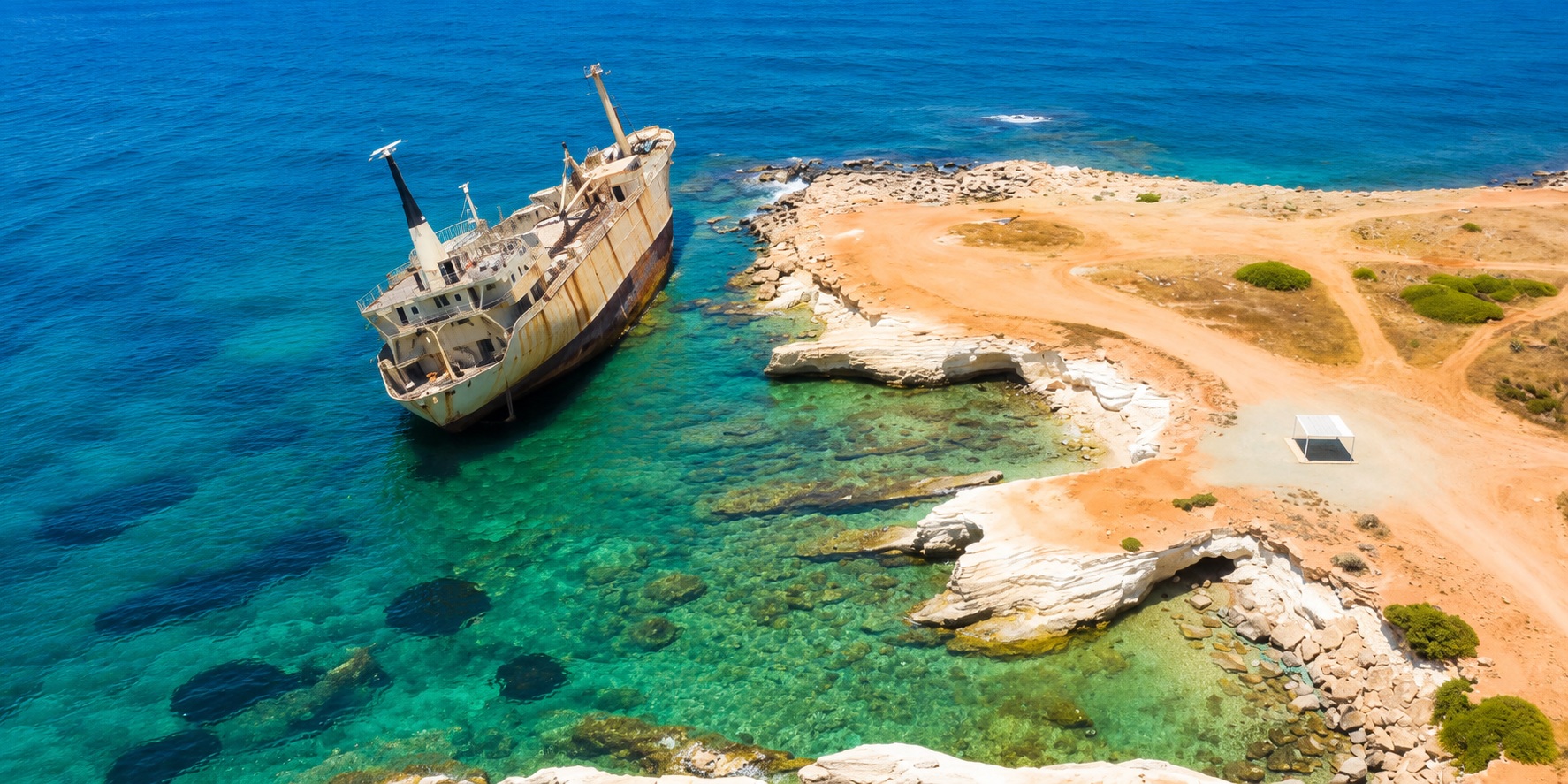 Aerial view of Edro III Shipwreck in shallow turquoise water near Sea Caves and Coral Bay, Paphos